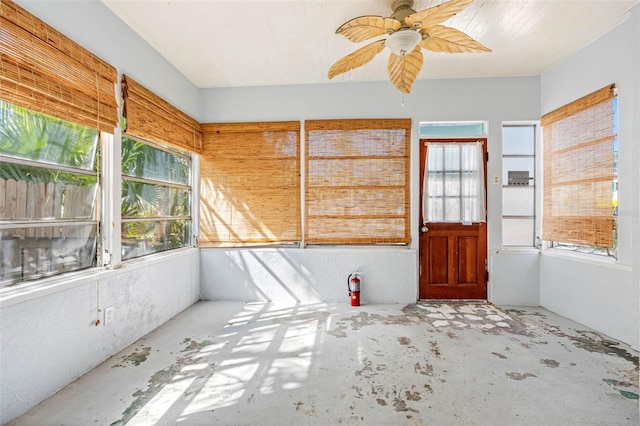 unfurnished sunroom featuring ceiling fan and a wealth of natural light