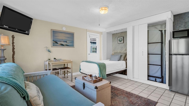 483 E Shore Dr Unit D4, Clearwater Beach, FL 33767 - bedroom with freestanding refrigerator, tile patterned flooring, and a textured ceiling