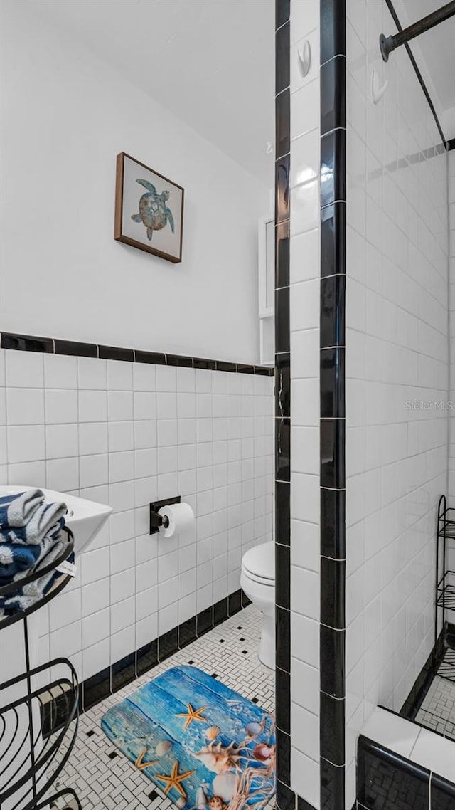 bathroom with tile patterned flooring, toilet, and tile walls