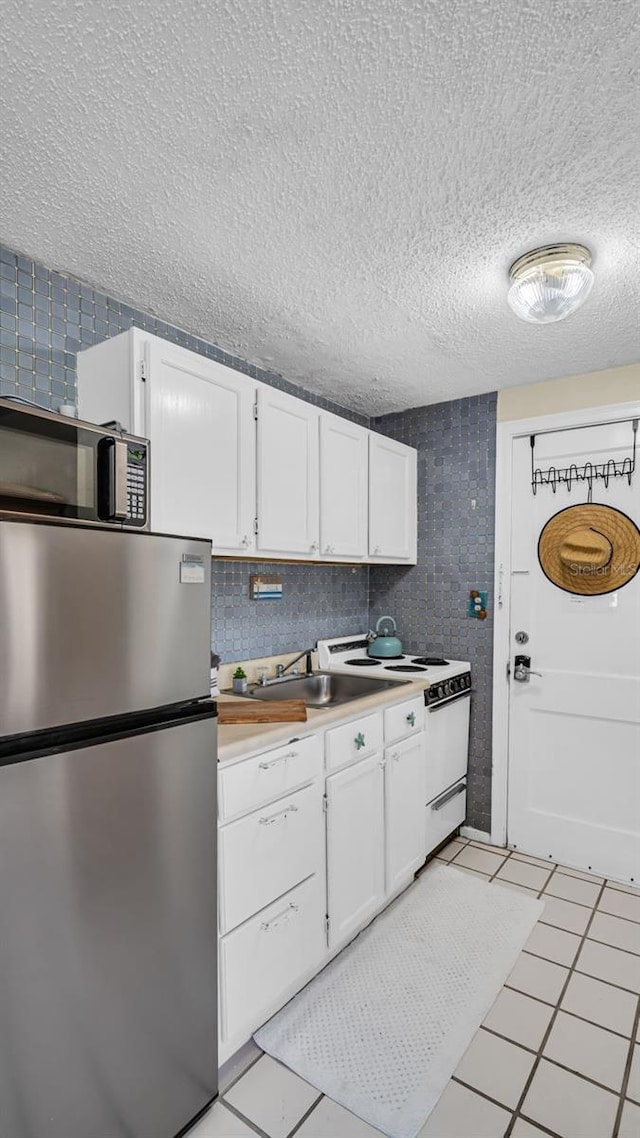 483 E Shore Dr Unit D4, Clearwater Beach, FL 33767 - kitchen featuring freestanding refrigerator, white electric range oven, black microwave, white cabinetry, and a textured ceiling