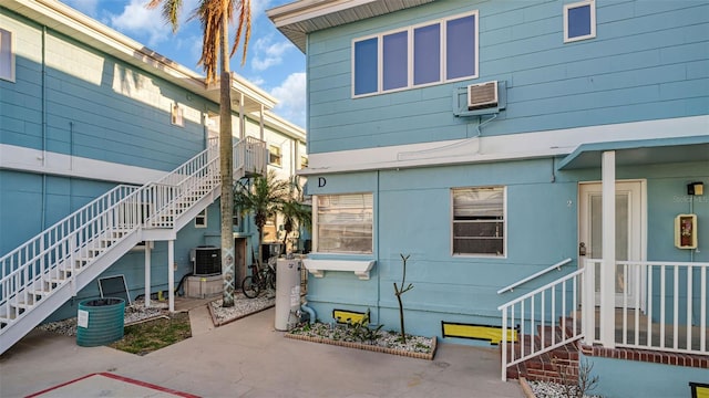483 E Shore Dr Unit D4, Clearwater Beach, FL 33767 - back of house with a patio, stairs, water heater, a wall mounted air conditioner, and cooling unit