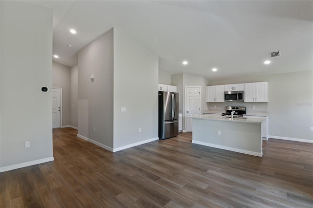 kitchen with white cabinets, dark hardwood / wood-style flooring, an island with sink, and stainless steel appliances