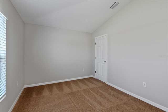 carpeted spare room featuring lofted ceiling