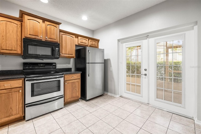 kitchen with french doors, light tile patterned flooring, a textured ceiling, and appliances with stainless steel finishes