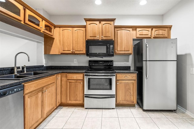 kitchen featuring light tile patterned flooring, sink, stainless steel appliances, and dark stone counters