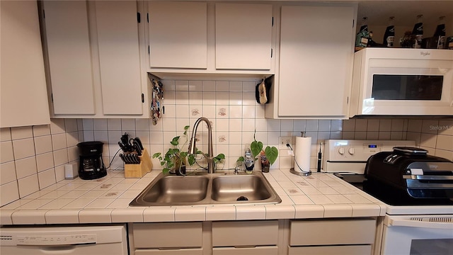 kitchen with tile counters, white cabinetry, sink, backsplash, and white appliances