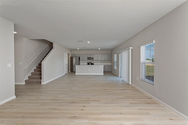 unfurnished living room with a textured ceiling and light hardwood / wood-style flooring