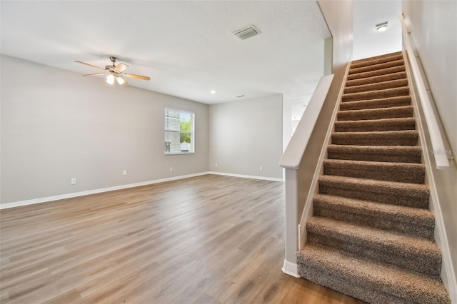 staircase featuring hardwood / wood-style floors and ceiling fan