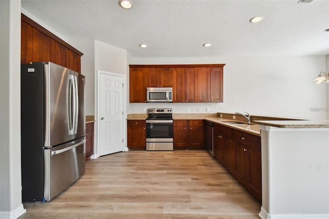 kitchen featuring sink, stainless steel appliances, a textured ceiling, and light hardwood / wood-style flooring