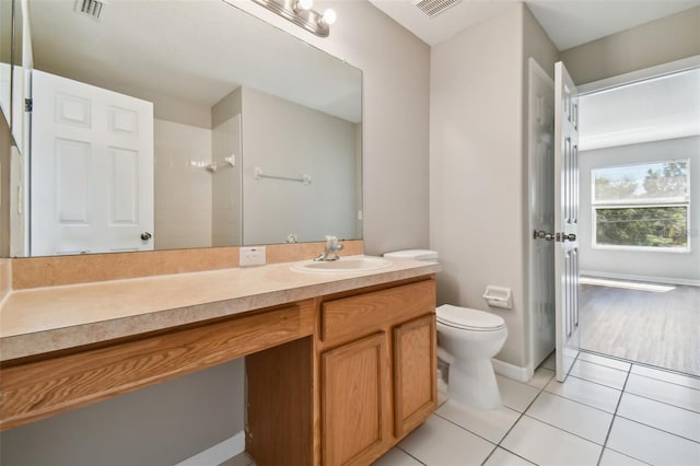 bathroom featuring toilet, vanity, tile patterned floors, and walk in shower