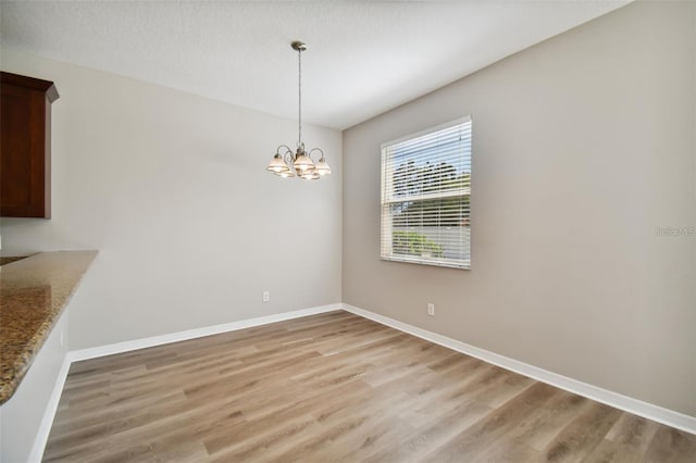 unfurnished dining area with light hardwood / wood-style floors and a notable chandelier