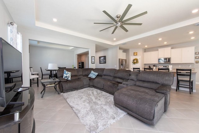 living room featuring light tile patterned floors, a tray ceiling, and ceiling fan