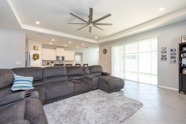 tiled living room featuring a tray ceiling and ceiling fan