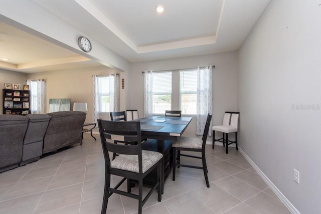 dining room with a tray ceiling and light tile patterned floors