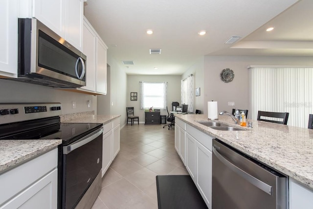 kitchen with white cabinets, appliances with stainless steel finishes, light stone counters, and sink