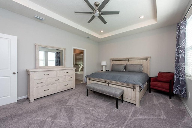 carpeted bedroom with a raised ceiling and ceiling fan