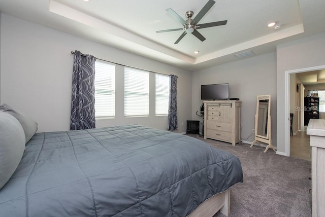 bedroom featuring ceiling fan, dark carpet, and a tray ceiling