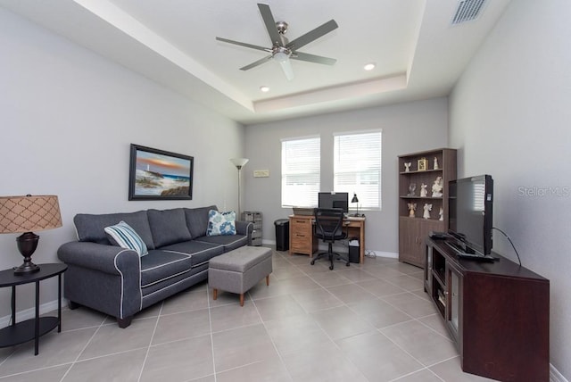 tiled living room featuring a raised ceiling and ceiling fan