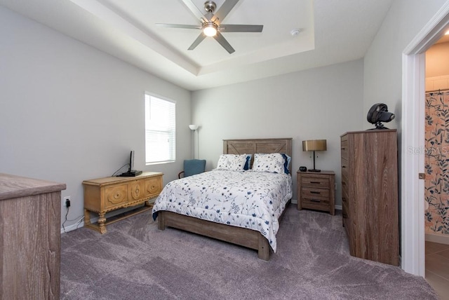 bedroom with a tray ceiling, ceiling fan, and dark colored carpet