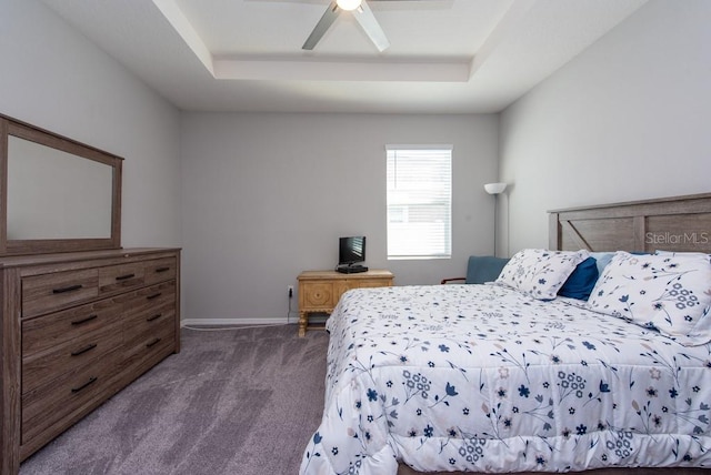 carpeted bedroom with ceiling fan and a tray ceiling