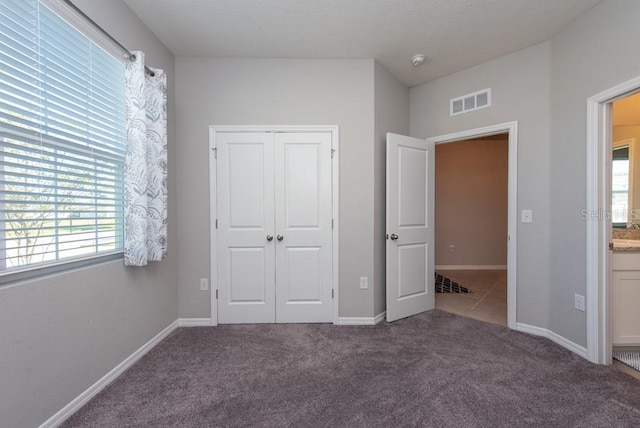 unfurnished bedroom featuring multiple windows, carpet floors, and a closet