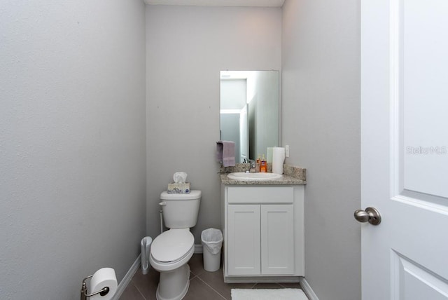 bathroom with toilet, vanity, and tile patterned floors