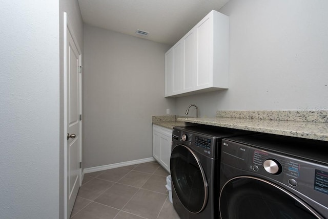 laundry room with cabinets, light tile patterned floors, and washing machine and clothes dryer