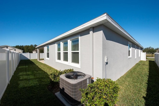 view of home's exterior featuring a lawn and central AC