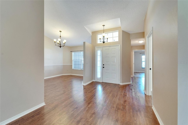 foyer featuring hardwood / wood-style flooring, a textured ceiling, and a notable chandelier