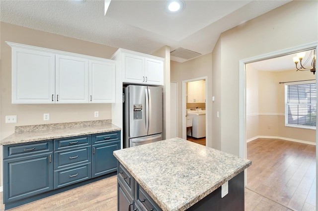 kitchen featuring blue cabinetry, white cabinetry, stainless steel refrigerator with ice dispenser, light hardwood / wood-style floors, and washer and dryer