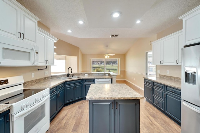 kitchen featuring blue cabinetry, appliances with stainless steel finishes, white cabinetry, and vaulted ceiling