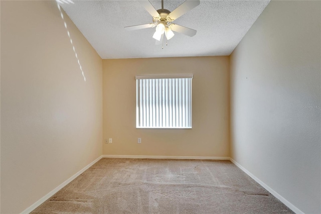 spare room with a textured ceiling, light colored carpet, and ceiling fan