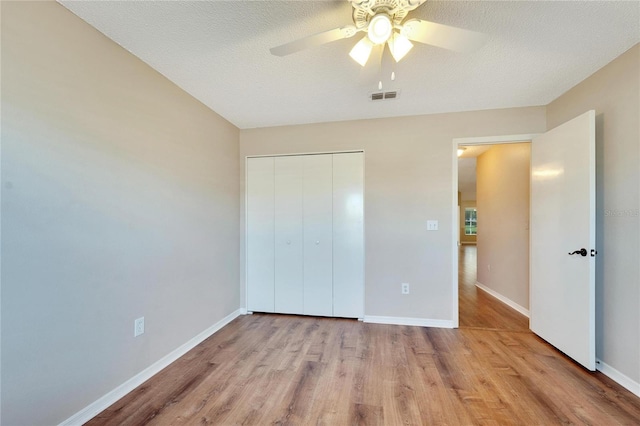 unfurnished bedroom featuring a closet, ceiling fan, light hardwood / wood-style flooring, and a textured ceiling