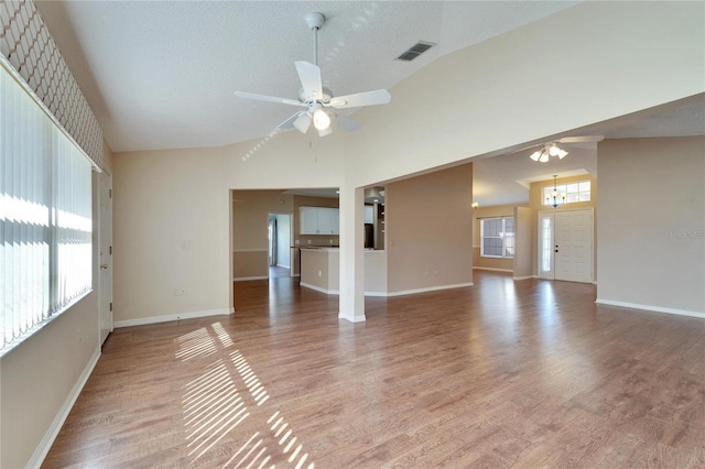 unfurnished living room with a textured ceiling, hardwood / wood-style flooring, high vaulted ceiling, and ceiling fan