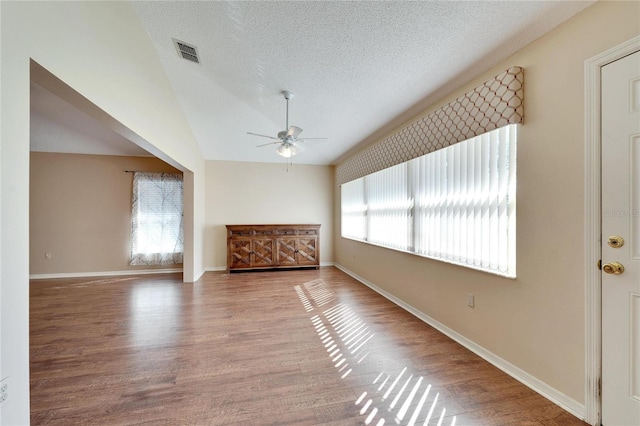 unfurnished living room featuring a textured ceiling, a wealth of natural light, vaulted ceiling, and hardwood / wood-style flooring