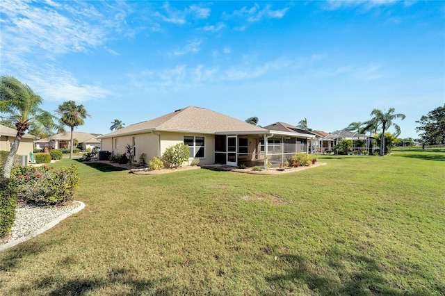 rear view of property with a sunroom and a lawn