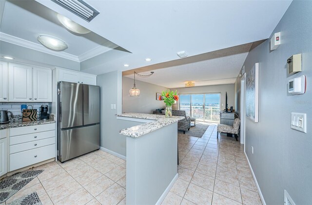 kitchen with white cabinets, crown molding, decorative backsplash, stainless steel fridge, and light stone counters