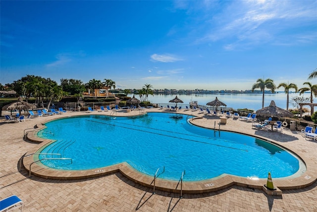 view of swimming pool featuring a patio and a water view