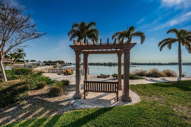 view of community featuring a pergola, a water view, and a lawn