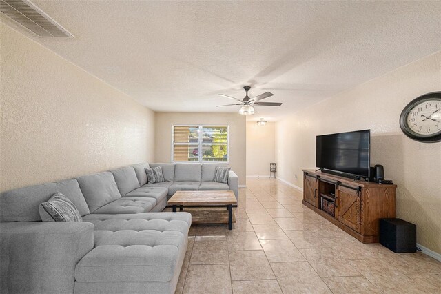 living room featuring ceiling fan, light tile patterned floors, and a textured ceiling