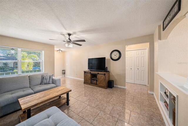 tiled living room with ceiling fan and a textured ceiling