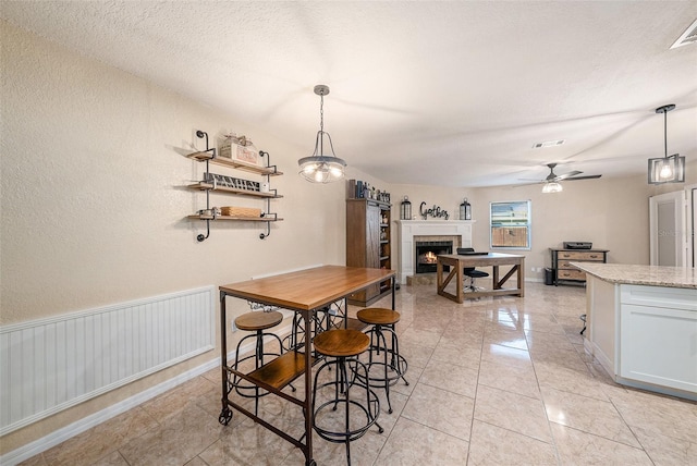 dining room featuring a tile fireplace and ceiling fan