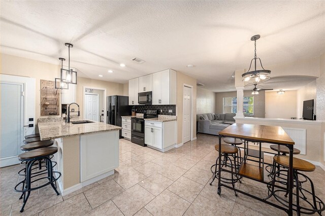 kitchen with pendant lighting, white cabinets, black appliances, and sink