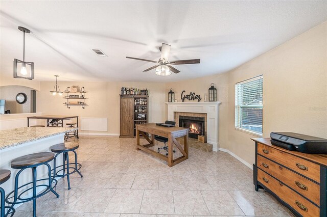 living room featuring ceiling fan and a tiled fireplace