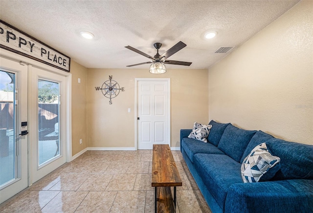 tiled living room with ceiling fan, french doors, and a textured ceiling