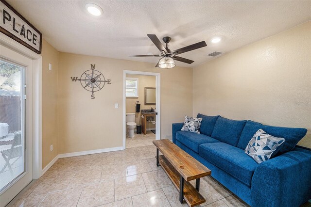 tiled living room featuring a textured ceiling and ceiling fan