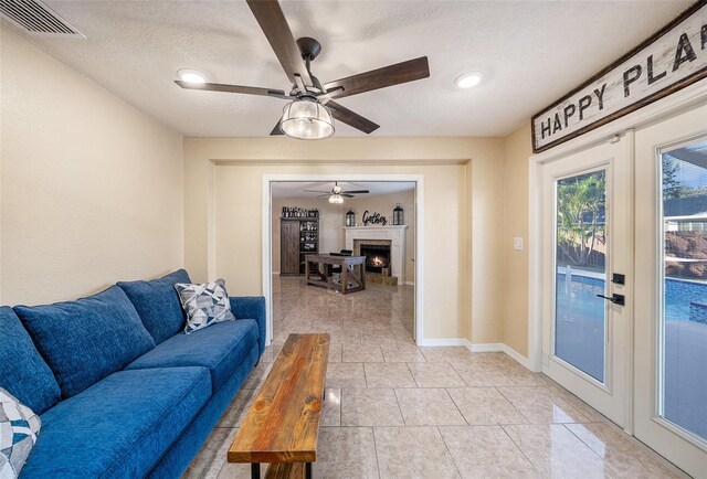 living room featuring ceiling fan, a textured ceiling, and french doors