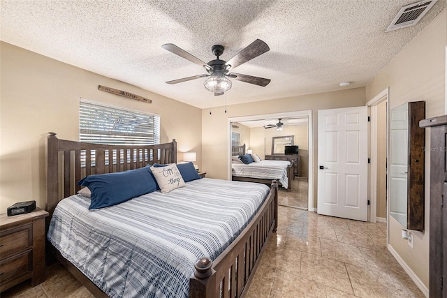 tiled bedroom with ceiling fan and a textured ceiling