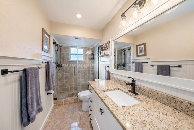 bathroom featuring tile patterned flooring, vanity, a shower with shower door, and toilet