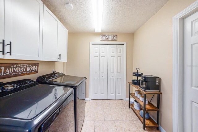 clothes washing area featuring washing machine and clothes dryer, light tile patterned floors, cabinets, and a textured ceiling